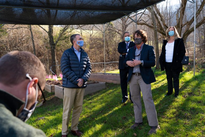 Four people including Gov. Ralph Northam stand in a wooded field.
